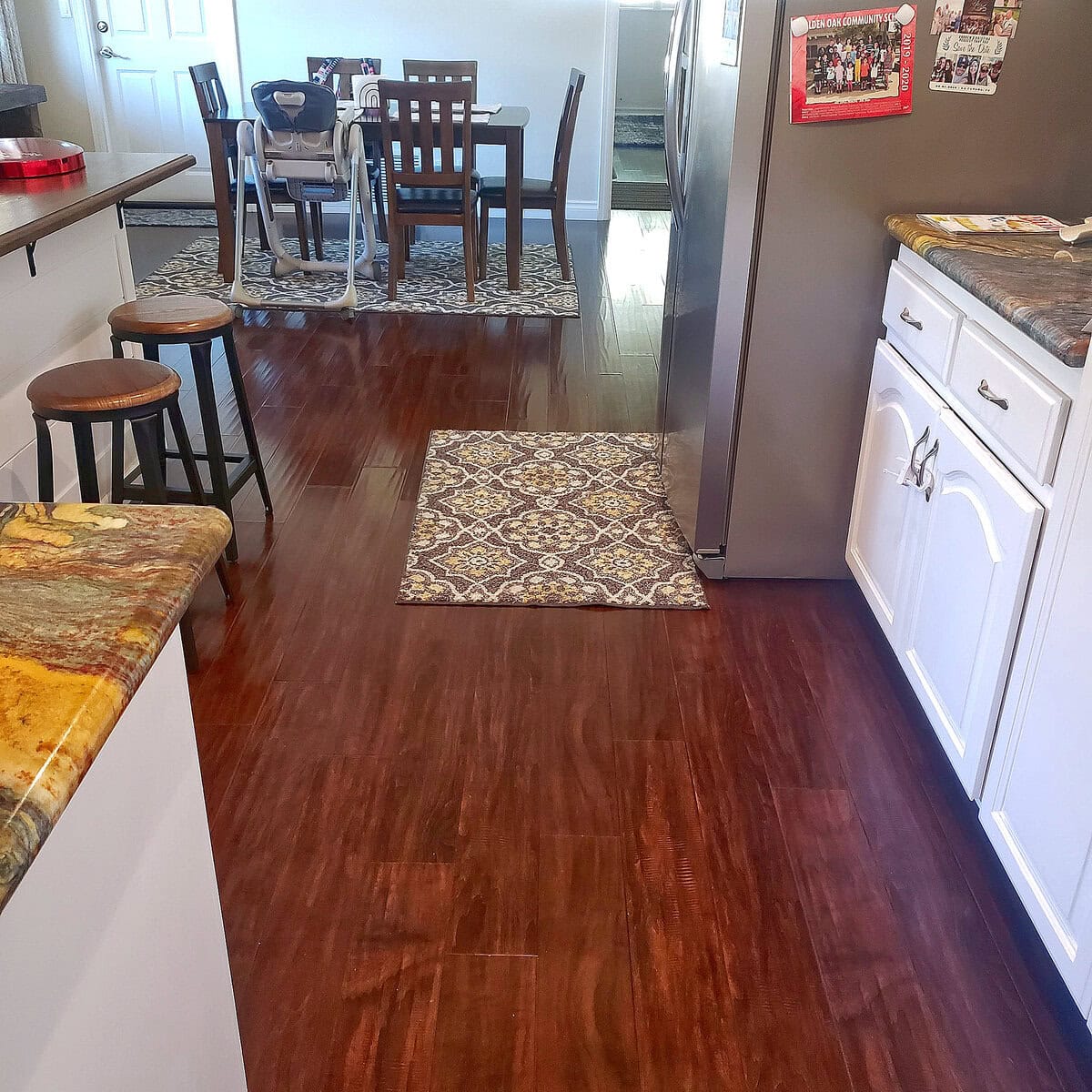 Bright, clean kitchen and dining area with shiny hardwood floors and decorative rugs, maintained by Cyclone Cleaning & Janitorial.