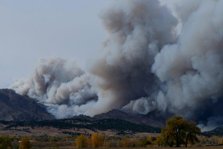 Thick wildfire smoke billowing over California hills during a major fire event, highlighting smoke damage risk to nearby homes.