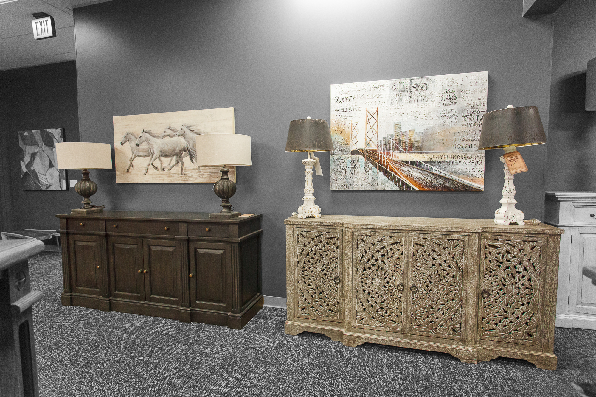 Hand-carved dark wood sideboard placed beneath framed automotive art and lamps.