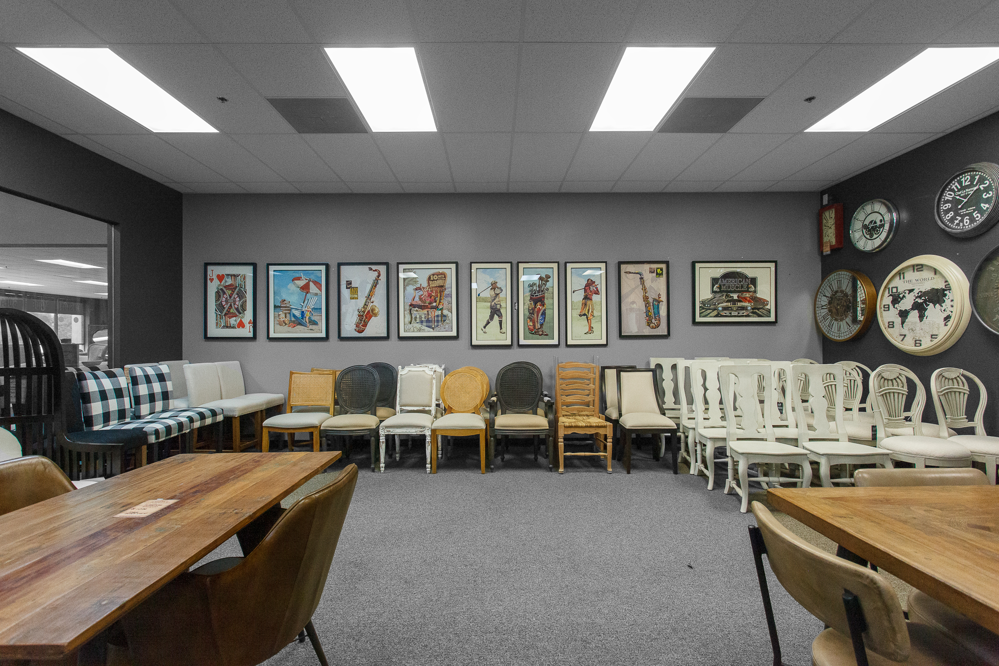 A room inside the store that has a collection of dining chairs, wall art, and clocks. 
