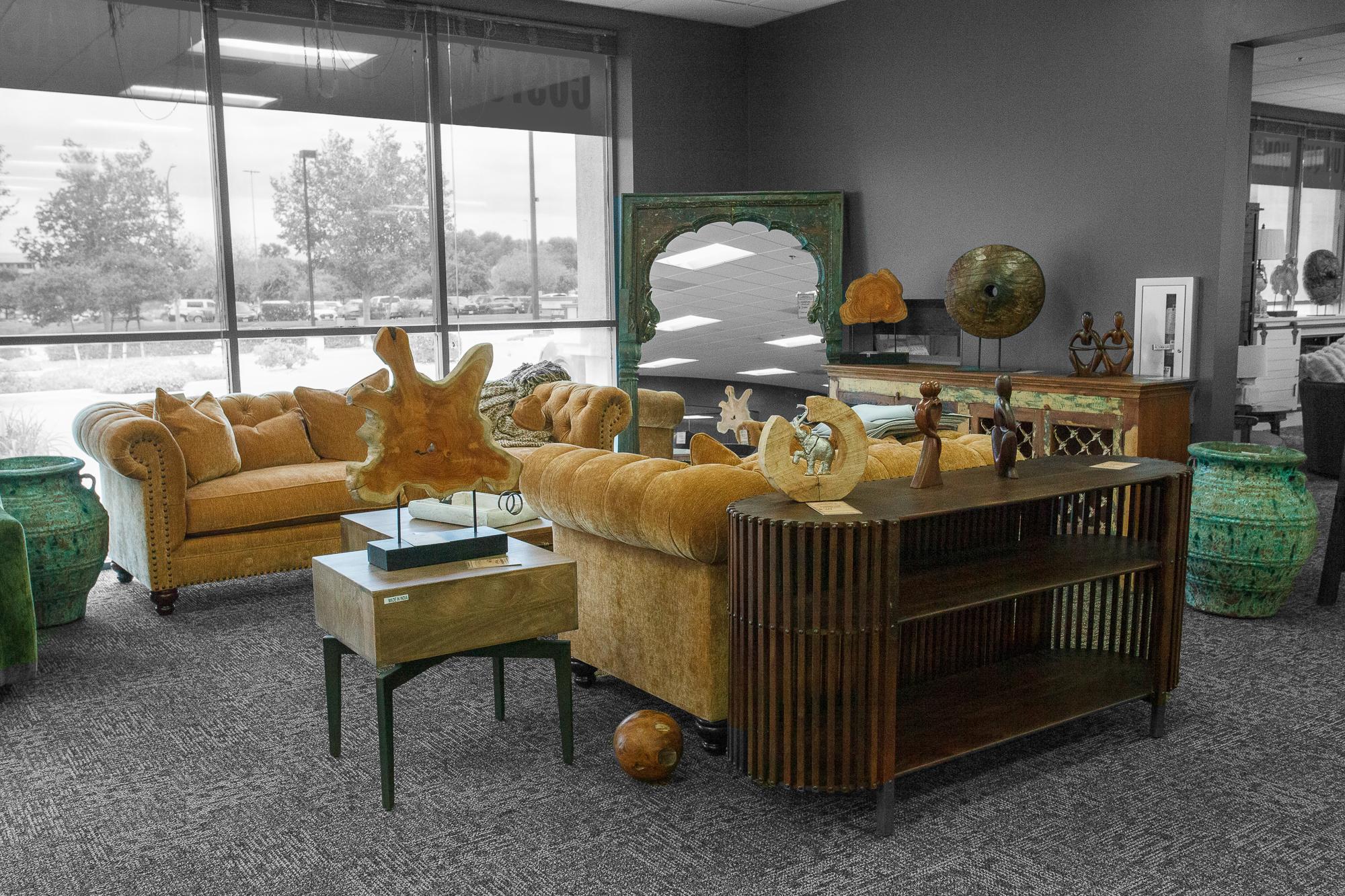Orange-ochre curved sofa with a rattan cabinet and lamps, placed in front of large showroom windows.