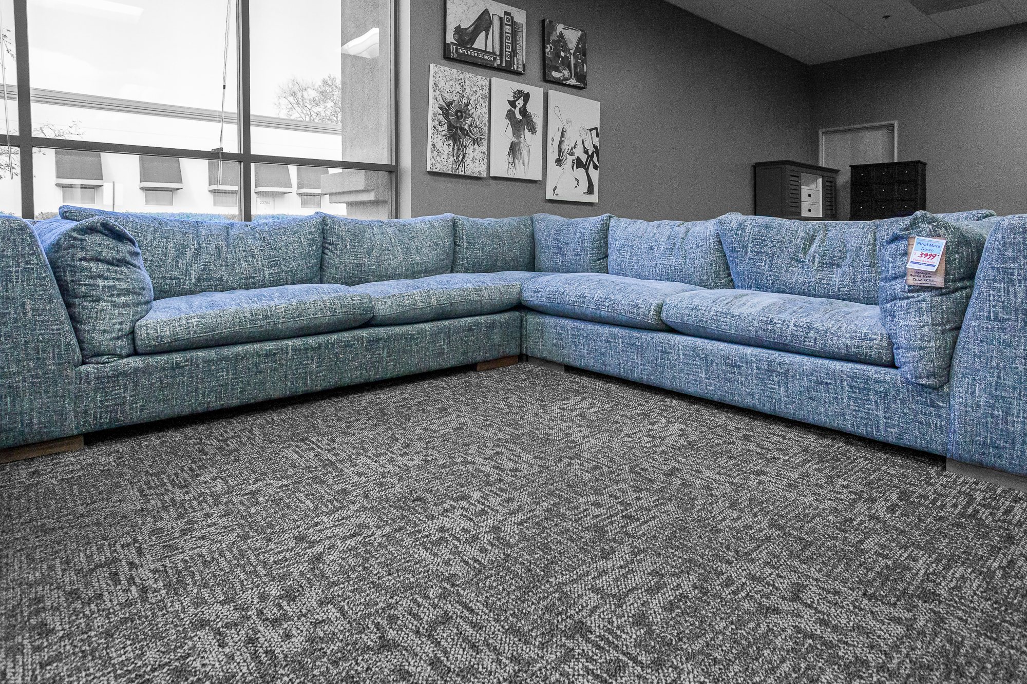 Spacious blue sectional couch in showroom corner, styled with casual pillows.