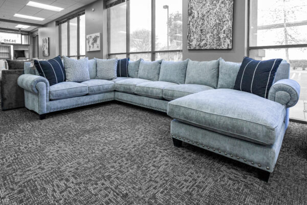 Large blue custom-made sectional with rounded arms and nailhead trim, styled with navy and patterned throw pillows.