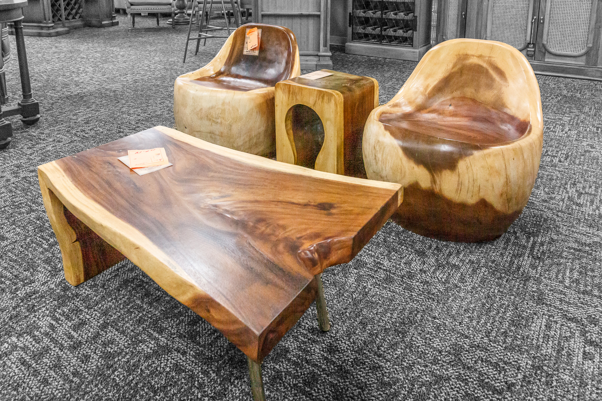 A live-edge wood coffee table with rounded, sculptural chairs and a matching wood side table.