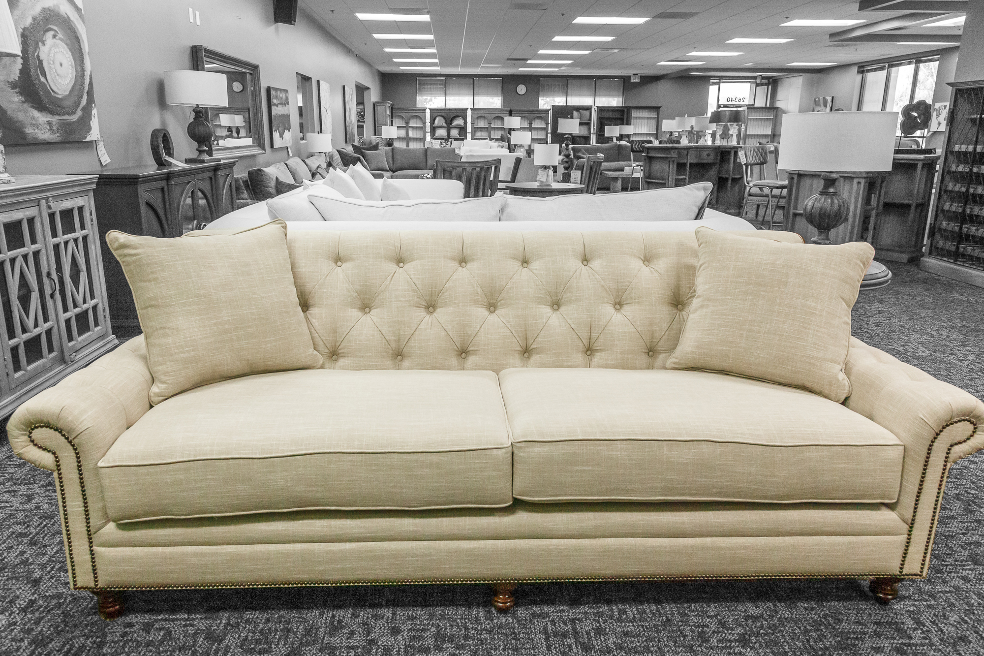 Cream-colored three-seater with classic tufted back and wooden legs.
