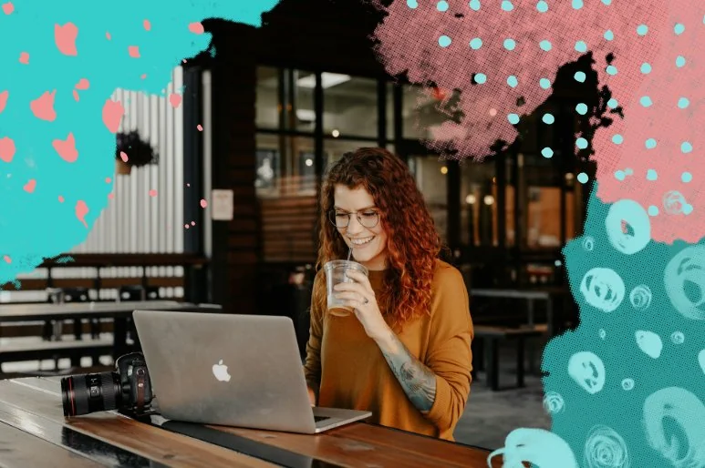 A photographer smiling while working on her laptop at a local coffee shop.